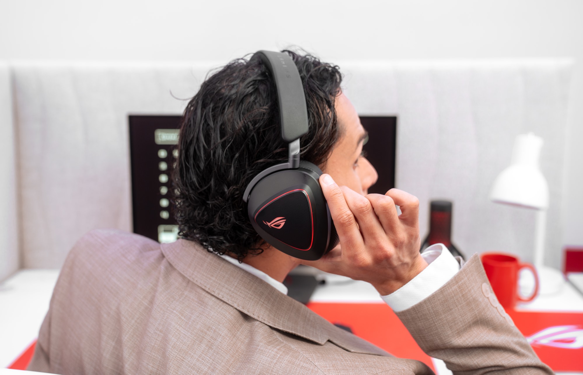 Một chàng trai trẻ trong bộ đồ quay lại nghe ai đó nói chuyện với anh ta, nâng chiếc cốc của mình