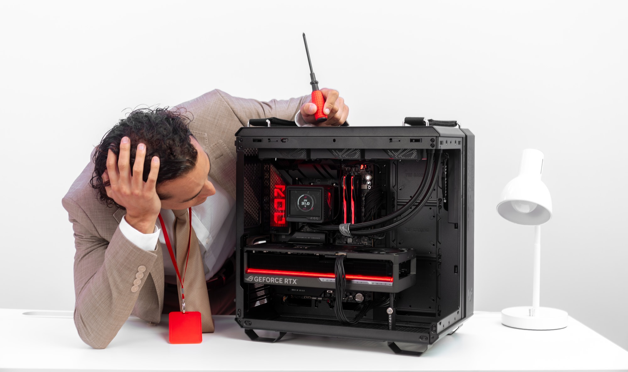 Một người đàn ông cúi xuống nhìn vào bên trong khung gầm của bản dựng PC đã hoàn thành, một tay trên trán và tay kia cầm tuốc nơ vít