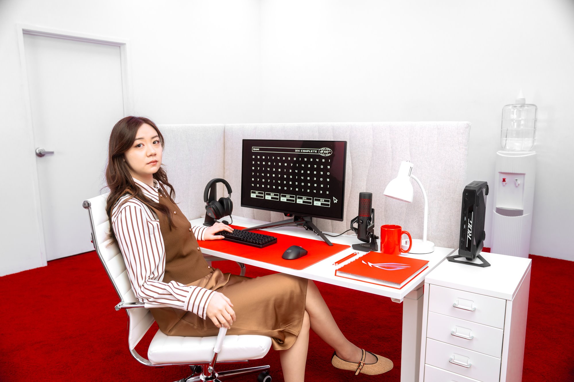 Một người phụ nữ ngả người vào ghế trong khi ngồi ở một bàn văn phòng đầy đủ các thiết bị rog